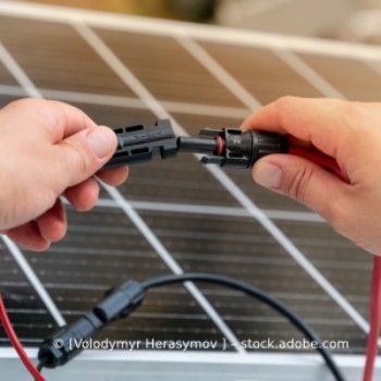 Eine Person verbindet Kabel mit einem Solarpanel, Volker Nitschke Elektro Stenglein