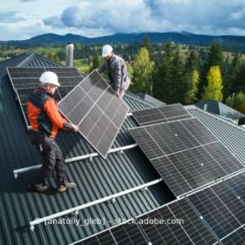 Zwei Männer installieren Sonnenkollektoren auf dem Dach eines Hauses, Volker Nitschke Elektro Stenglein