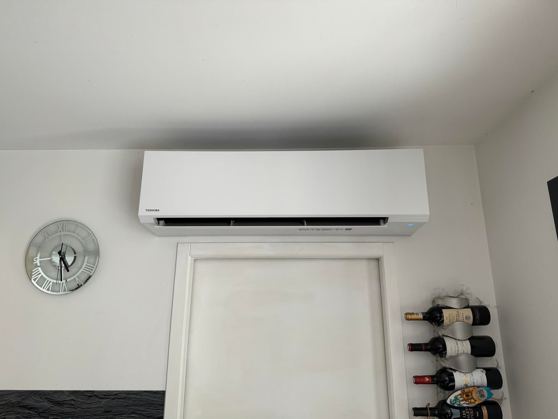 Un climatiseur blanc fixé au-dessus d'une porte blanche.