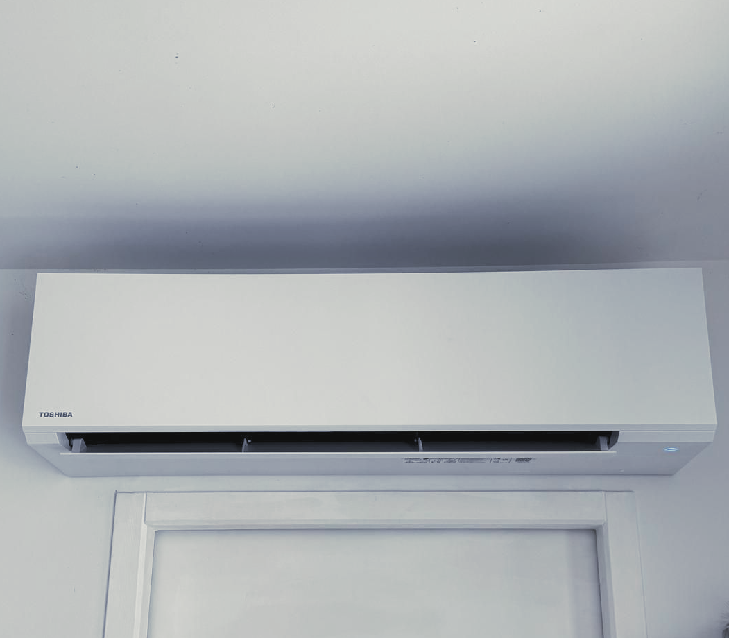 Climatiseur blanc fixé au-dessus d'une porte sur un mur.