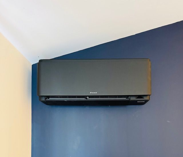 Unité de climatisation blanche fixée sur un mur.