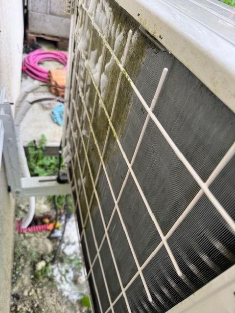 Une personne portant des gants noirs manipule les manomètres d'un climatiseur.