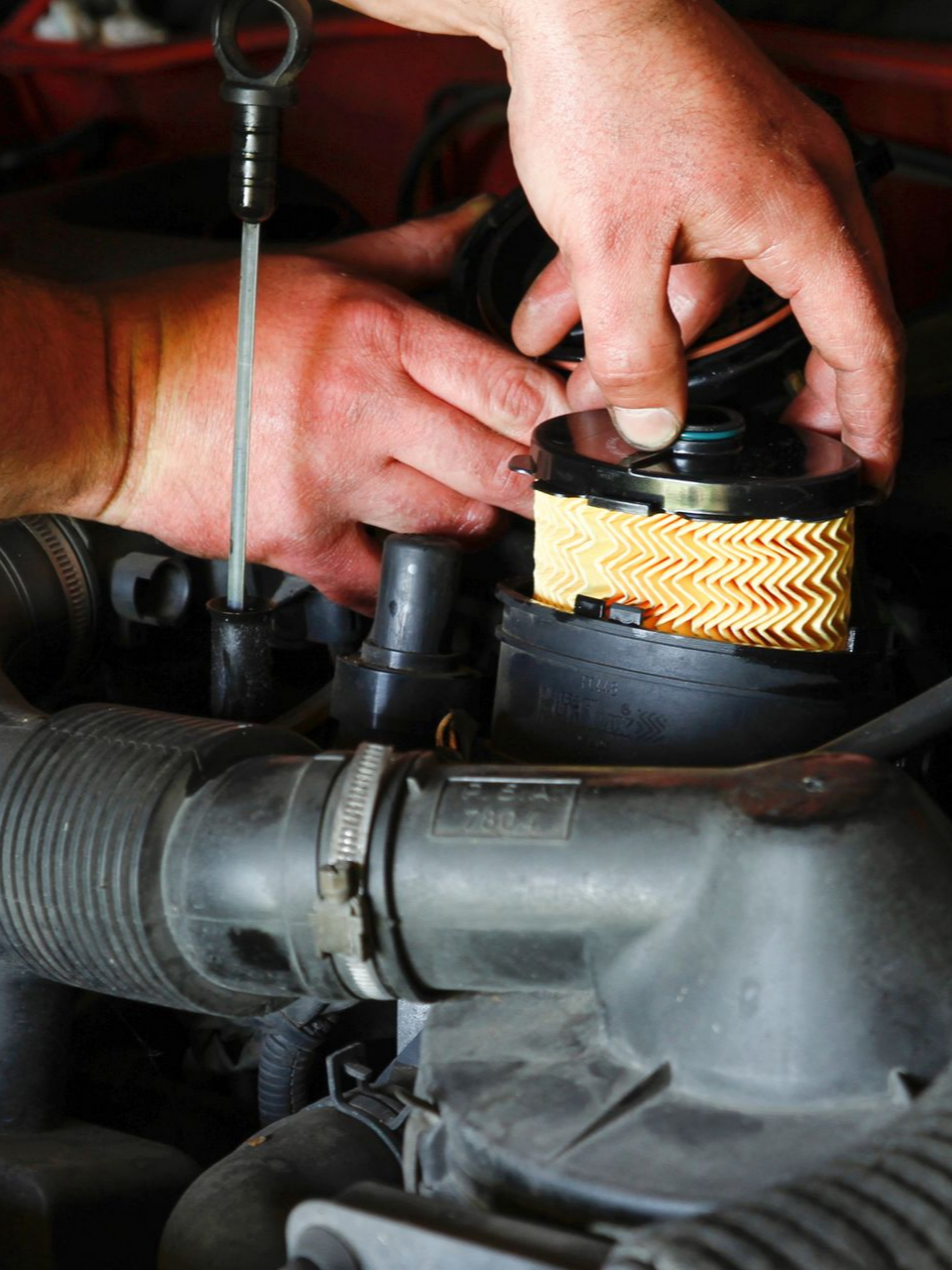 Des mains remplacent un filtre à huile plissé dans le compartiment moteur d'une voiture.