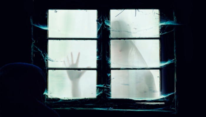 Silhouette of a figure behind a cracked window, reaching a hand out. Dark setting, eerie atmosphere.