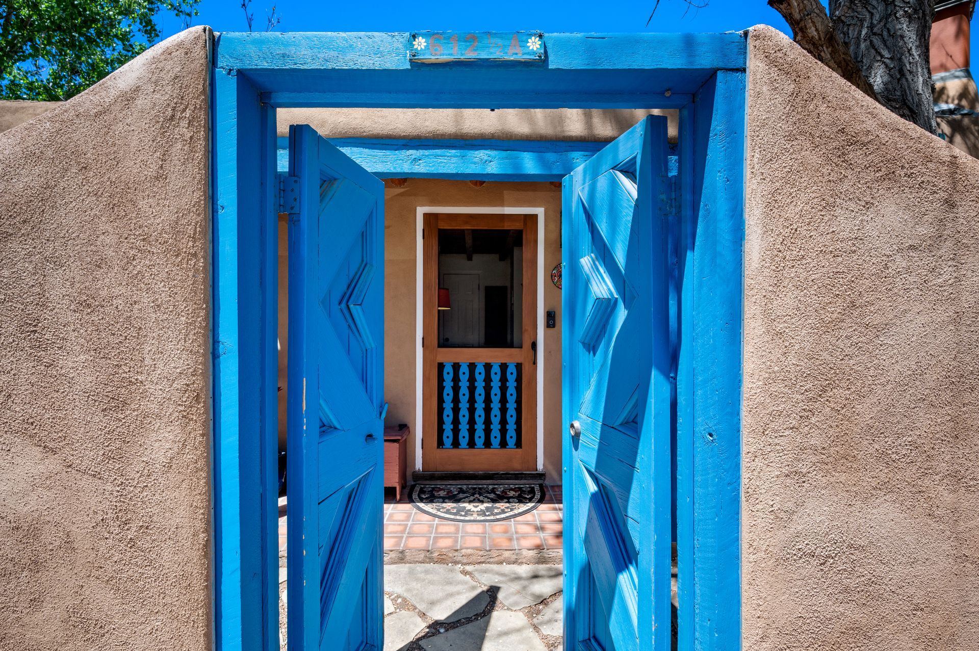 Blue wooden doors opening to a brown stucco archway; interior door visible.