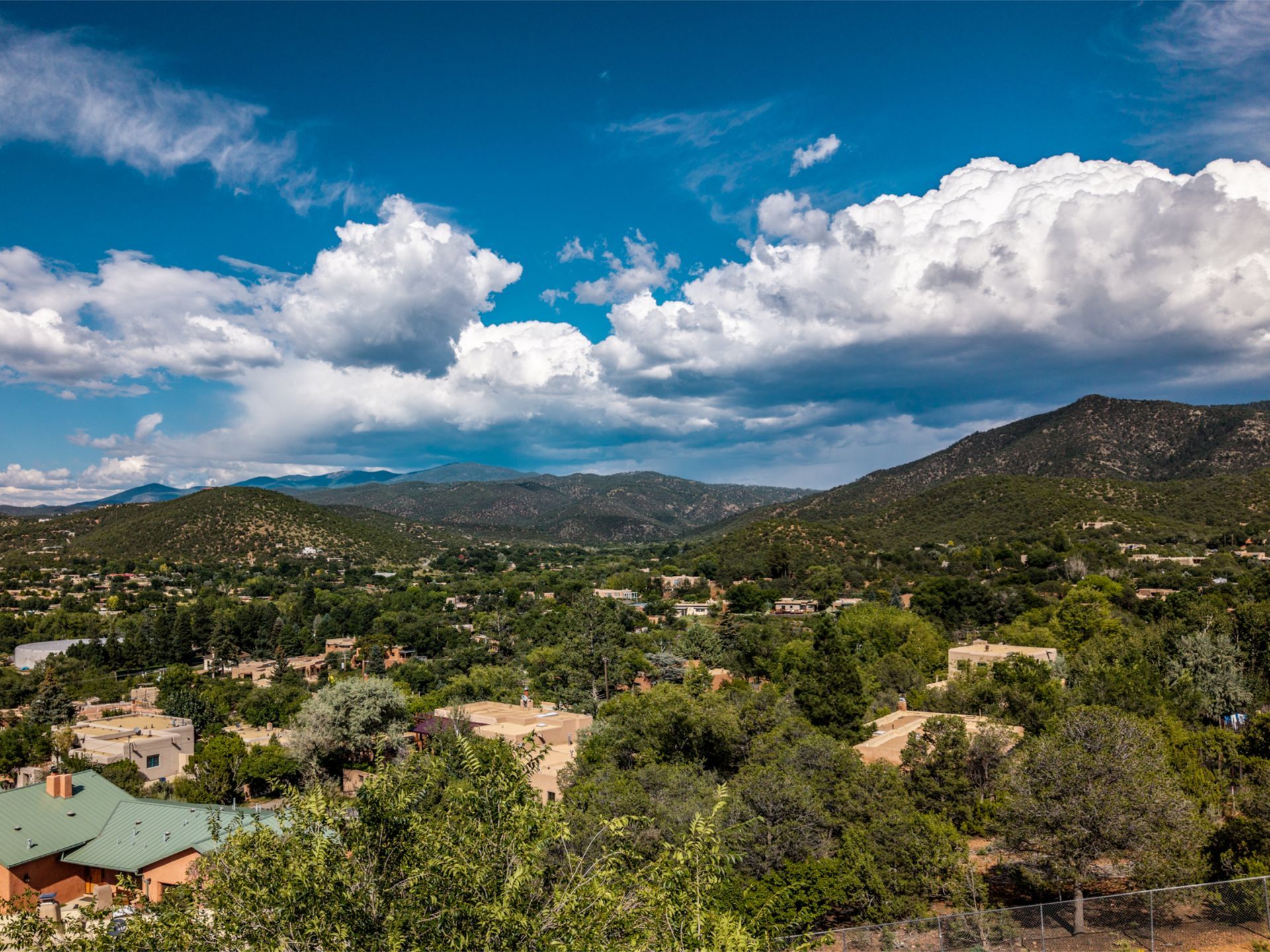 Santa Fe Mountains and Neighborhoods under a blue sky with puffy white clouds.