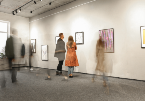 People viewing artwork in a gallery, neutral walls and lighting.