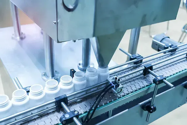 Una máquina está moviendo botellas en una cinta transportadora en una fábrica.