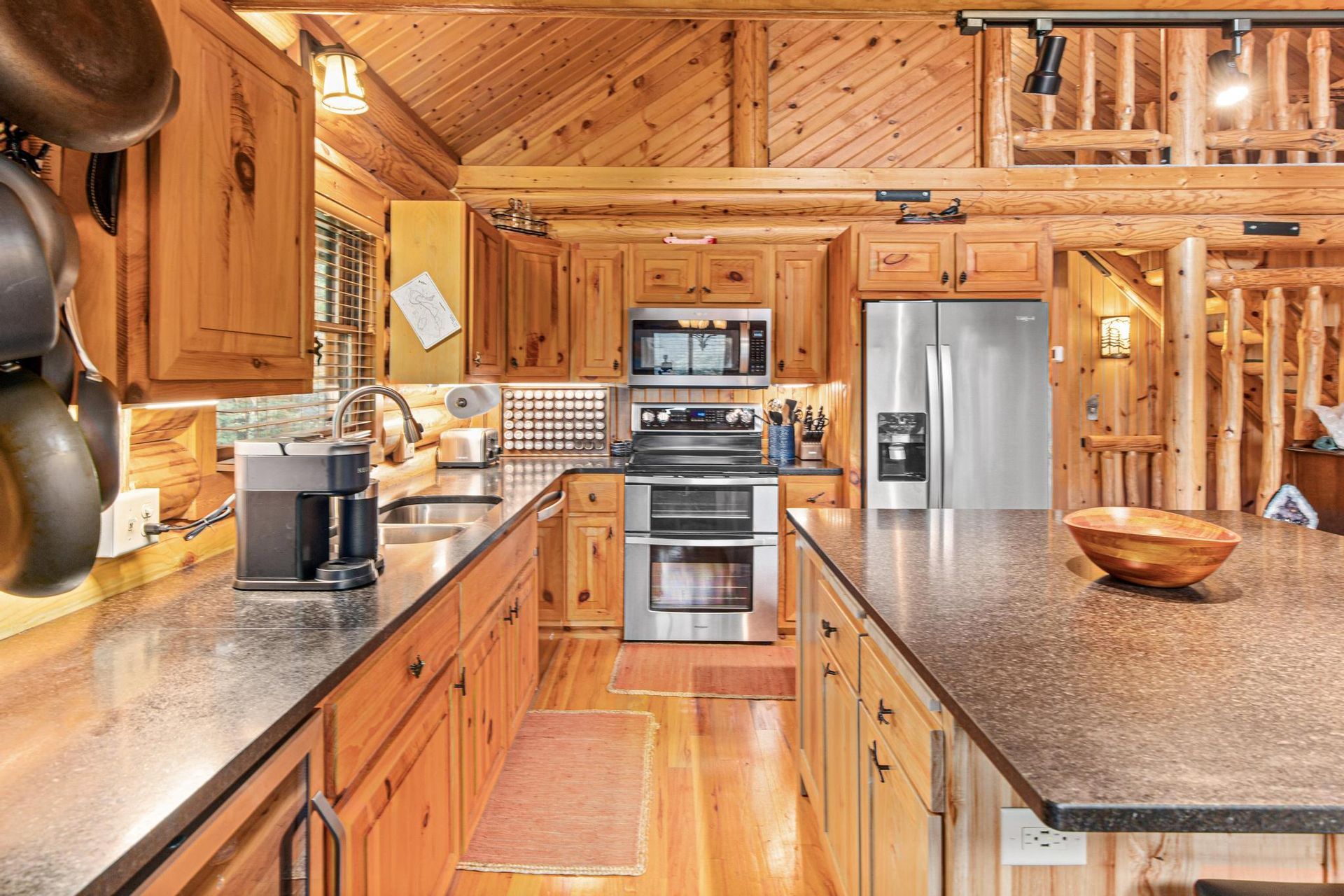 A kitchen in a log cabin with stainless steel appliances and granite counter tops.
