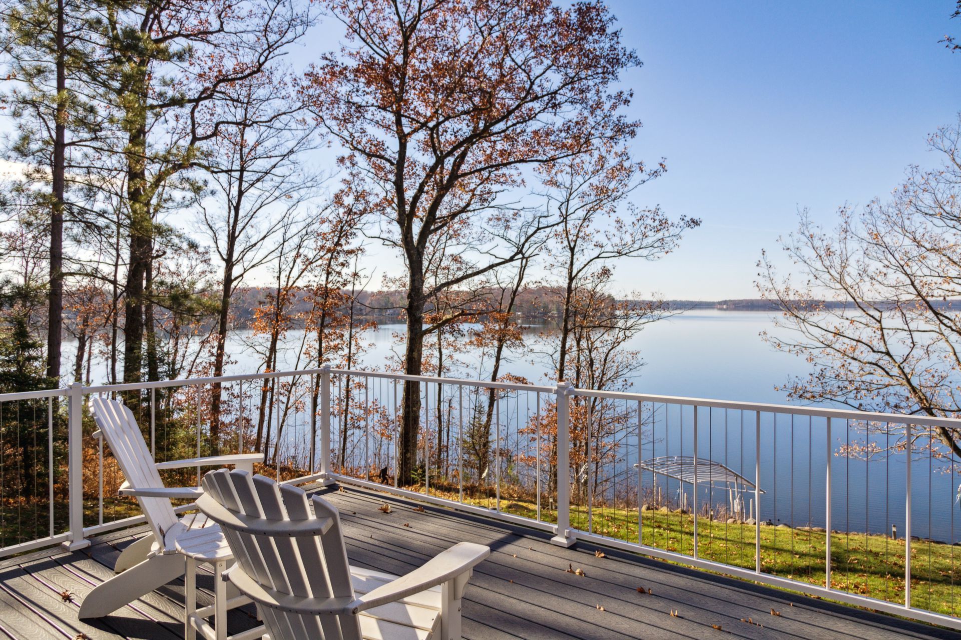 Two chairs are sitting on a deck overlooking a lake.
