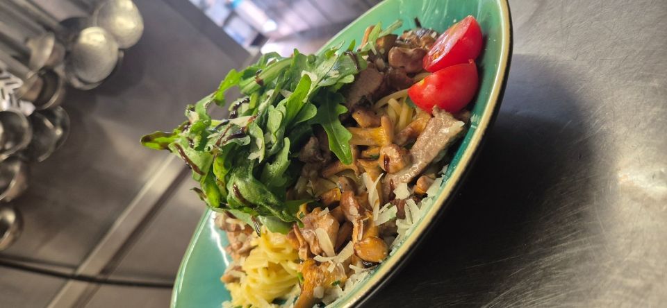 Salatschüssel mit Blattsalaten, Tomaten, Oliven und geraspelten Toppings auf einer Edelstahltheke