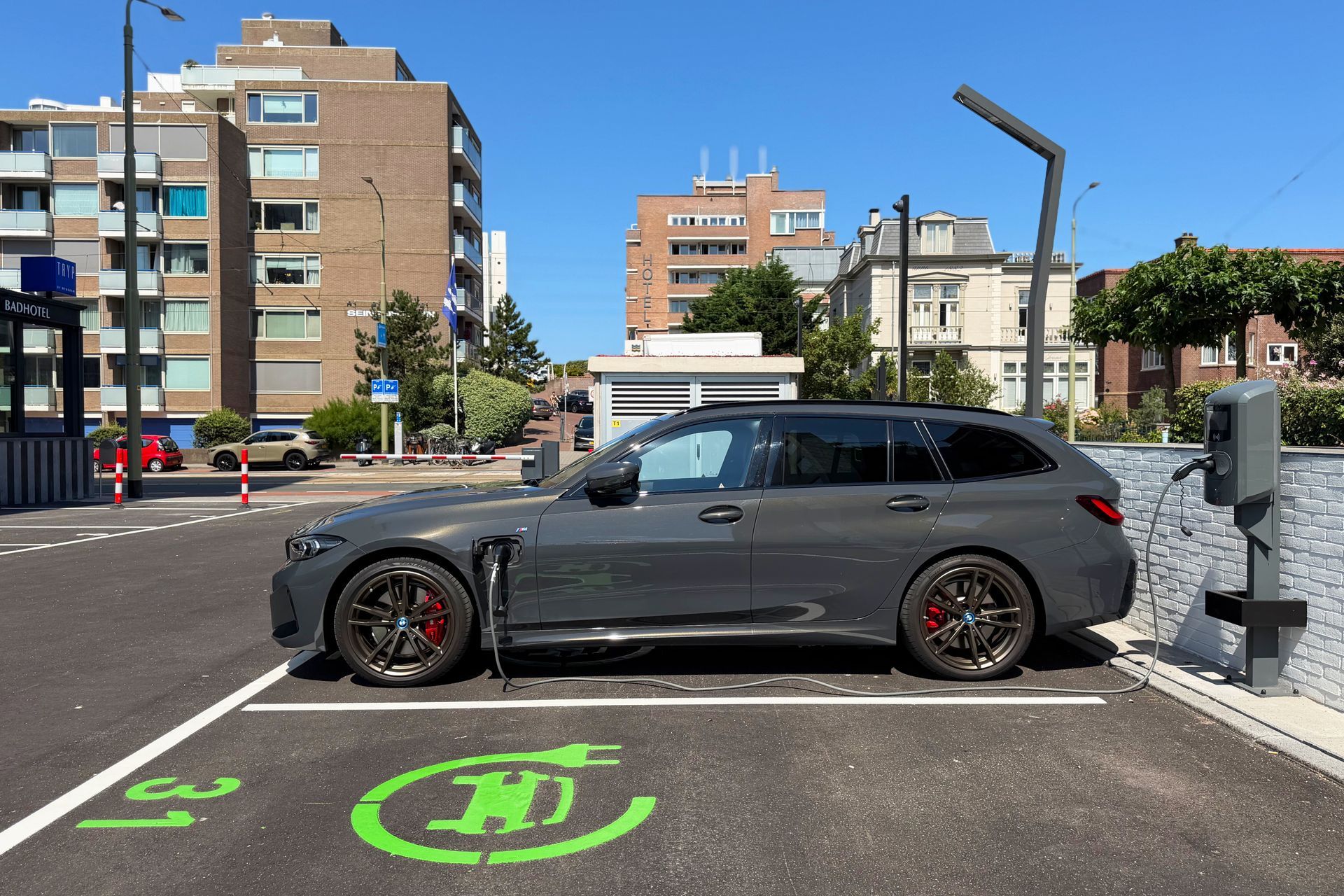 De elektrische auto is aangesloten op een laadstation, met een kabel verbonden met de aansluiting aan de achterkant.