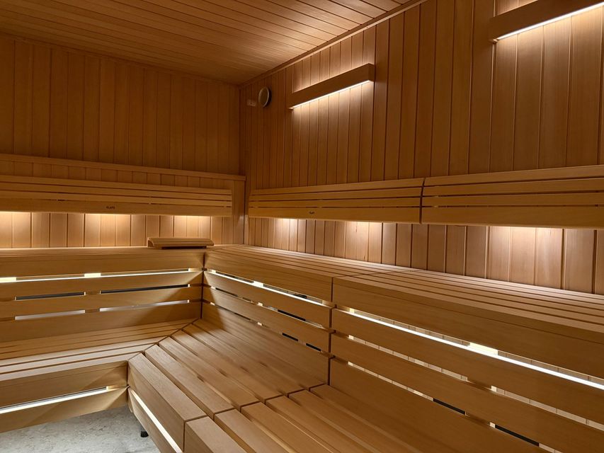 Houten sauna-interieur met lattenbanken en warme sfeerverlichting.