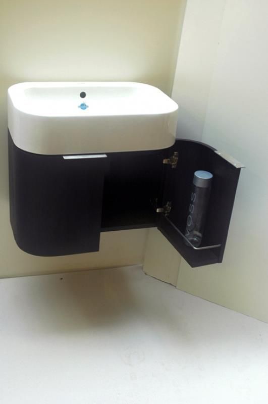 Ein Waschbecken im Badezimmer mit offener Tür und einer Flasche darin