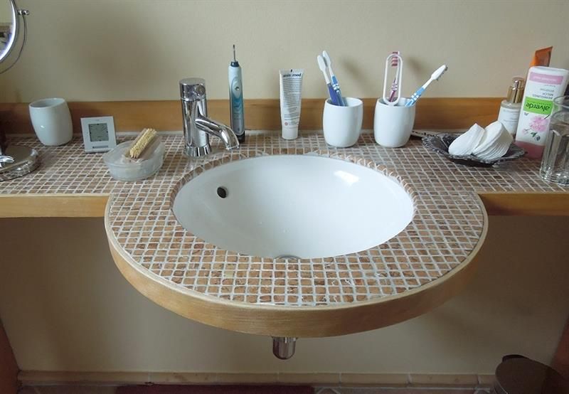 Ein Waschbecken im Badezimmer mit Zahnbürsten und Zahnpasta darauf