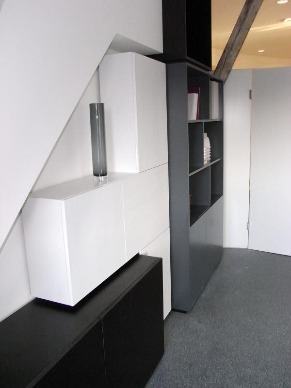 Eine Zimmerecke mit weißen Schränken und schwarzen Regalen