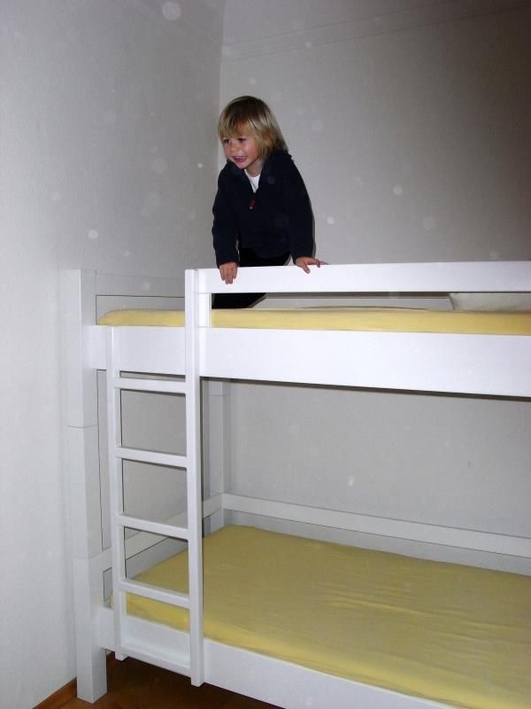 Ein kleiner Junge steht auf einem Etagenbett