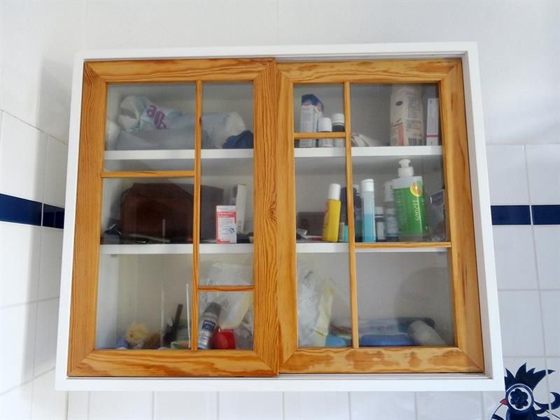 Ein Badezimmerschrank mit einer Flasche Lotion auf dem untersten Regal