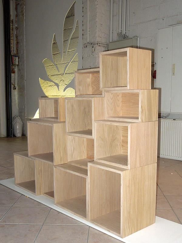 Ein Stapel Holzregale mit einem Blatt an der Wand dahinter
