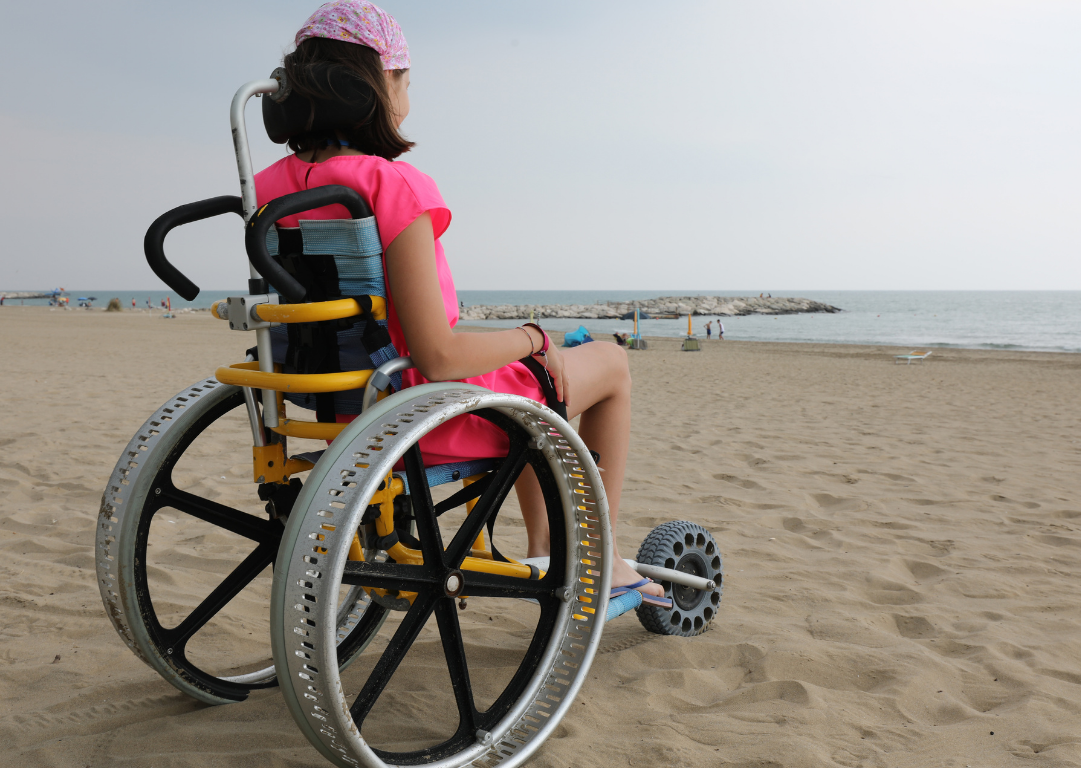 Girl in an adapted wheelchair on the beach on holiday