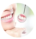 Una mujer se mira los dientes en un espejo.