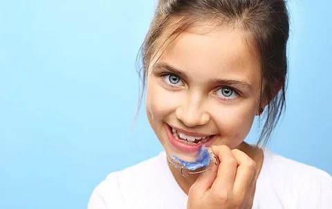 Una niña con aparatos dentales está sonriendo.