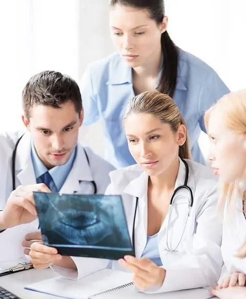 Un grupo de médicos está mirando una radiografía de los dientes de un paciente.