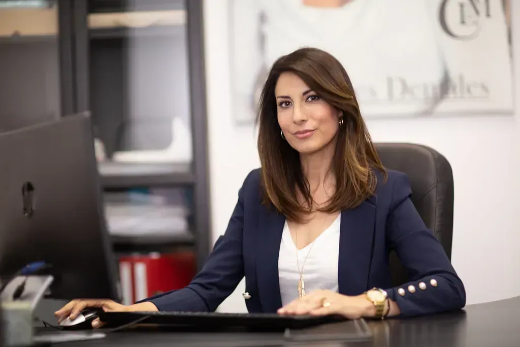Una mujer está sentada en un escritorio frente a una computadora.