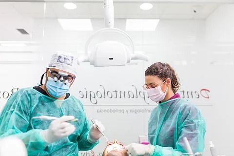 Un dentista y una enfermera están trabajando con un paciente en un consultorio dental.