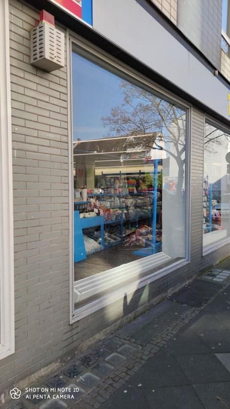 Eine Ladenfront mit einem großen Fenster und einer Backsteinmauer.