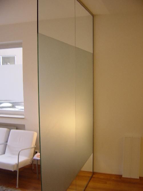 Ein Zimmer mit einer Couch und einem Sessel hinter einer Glaswand