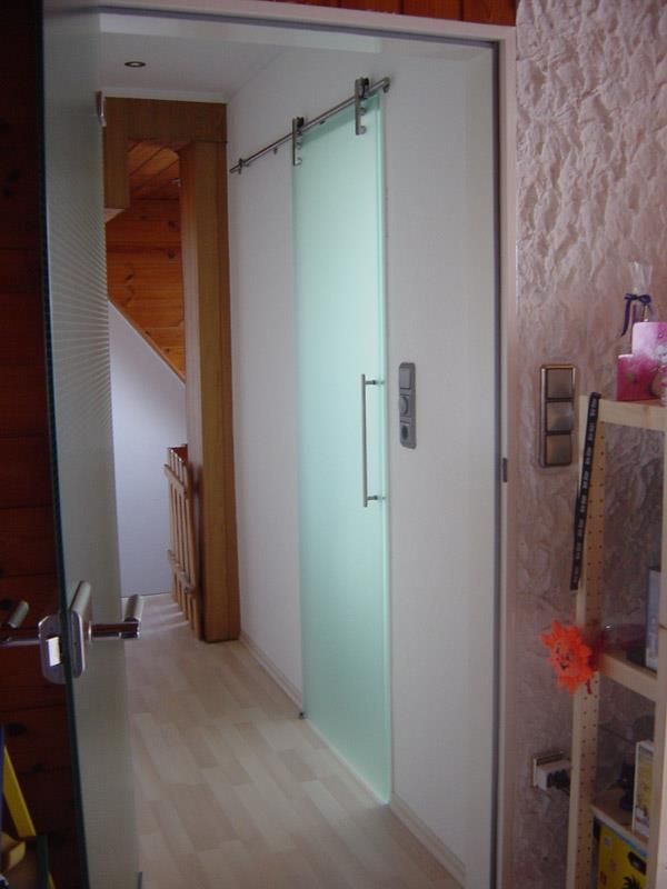 Ein Flur mit einer Glasschiebetür und einem Regal.