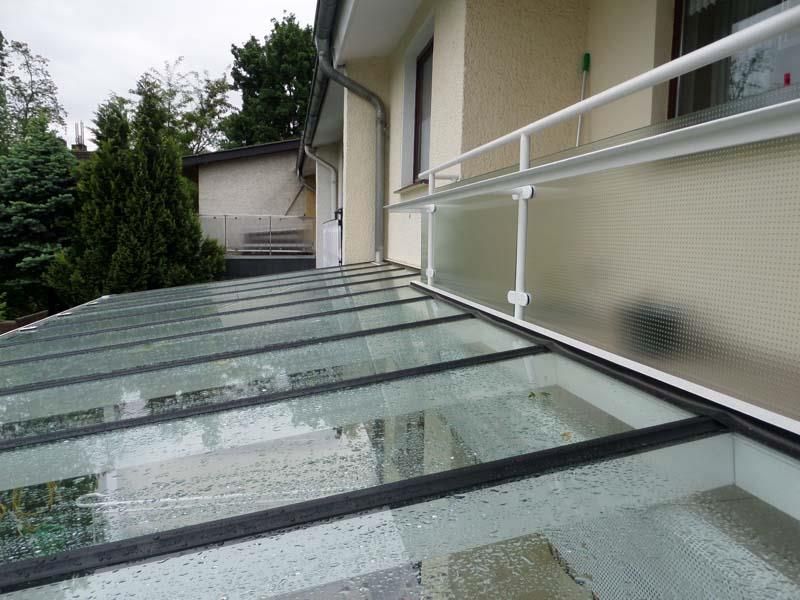 Ein Balkon mit Glasdach und weißem Geländer.