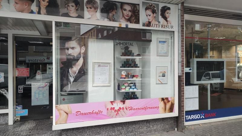 Ein Friseursalon mit vielen Bildern im Fenster.
