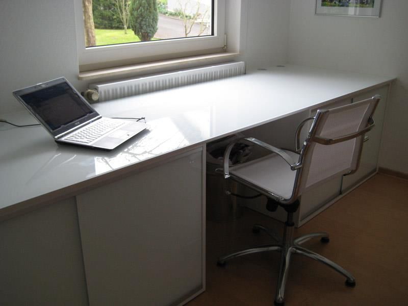 Ein Laptop steht auf einem Schreibtisch neben einem Stuhl