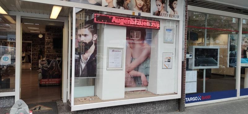 Ein Friseursalon mit einem bärtigen Mann im Fenster.