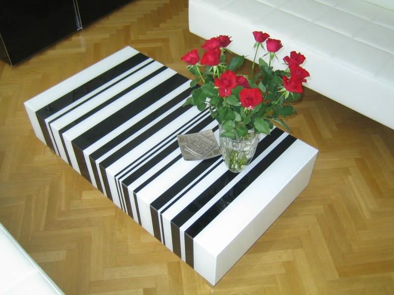 Ein schwarz-weiß gestreifter Couchtisch mit einer Vase mit roten Rosen darauf