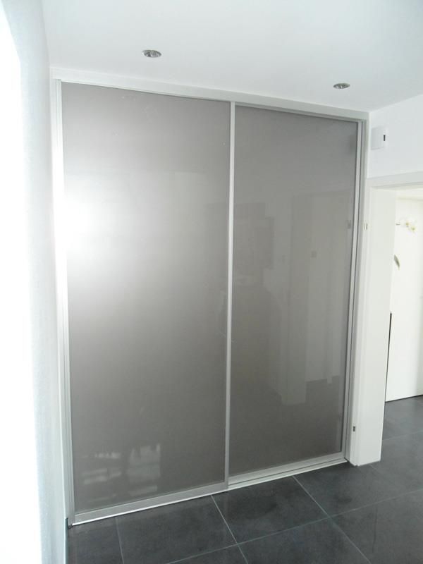 In einem Raum neben einem Fenster befindet sich eine Glasschiebetür.