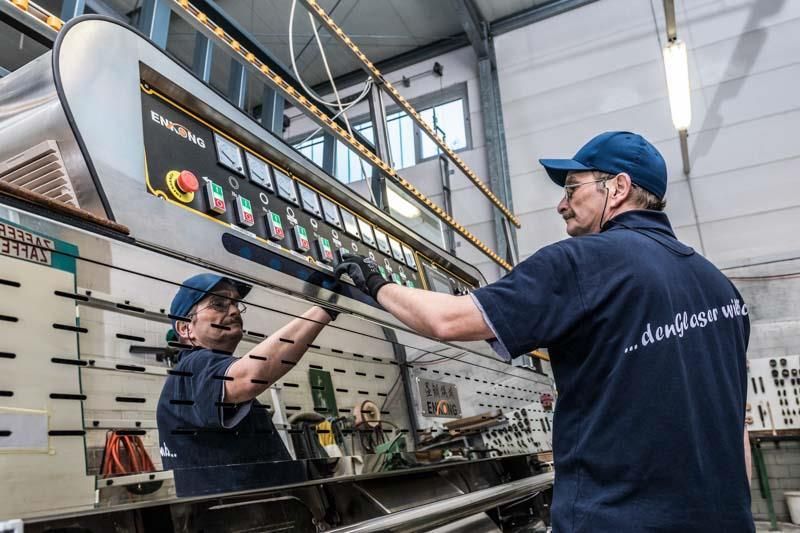 Zwei Männer arbeiten in einer Fabrik an einer Maschine.
