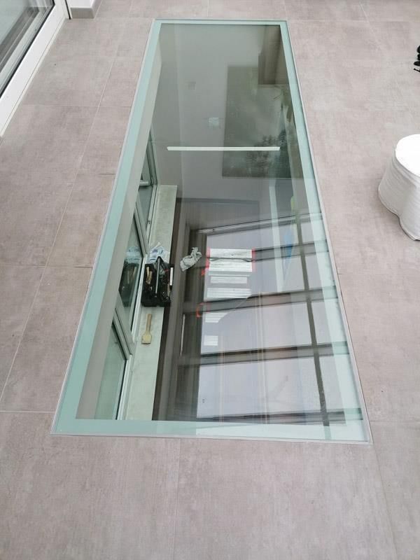 Ein Glasboden mit der Spiegelung eines Gebäudes darin