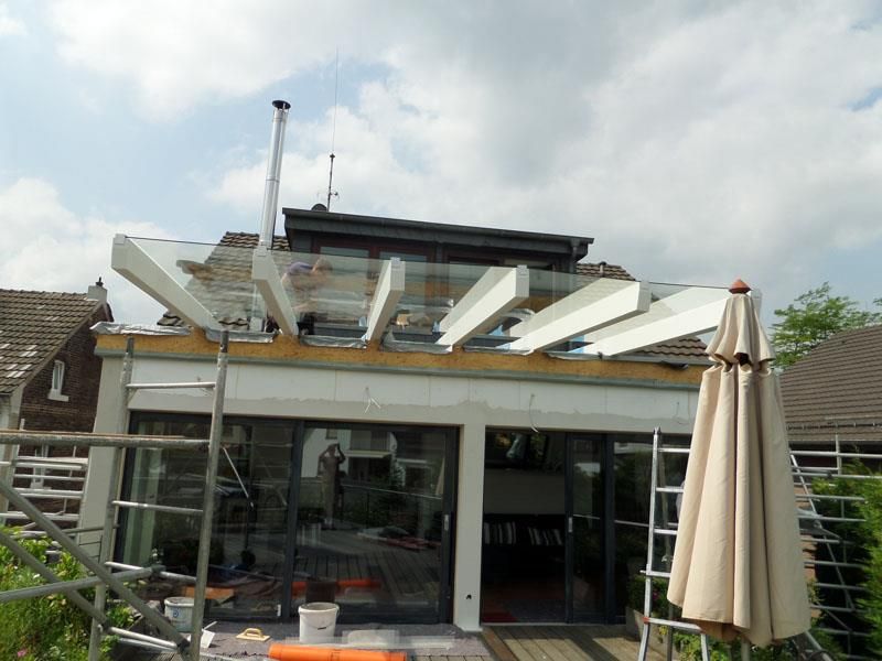 Ein Haus mit einem Glasdach und einem weißen Regenschirm davor