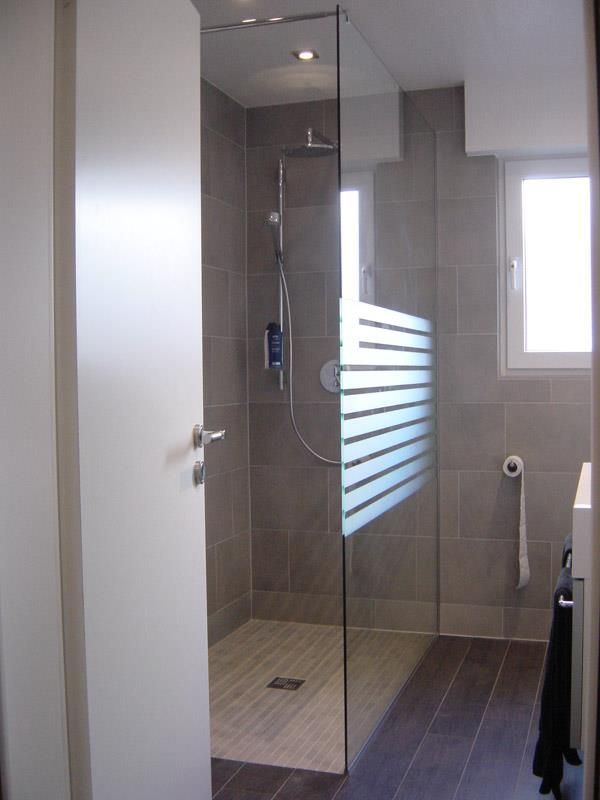 Ein Badezimmer mit ebenerdiger Dusche und Fenster