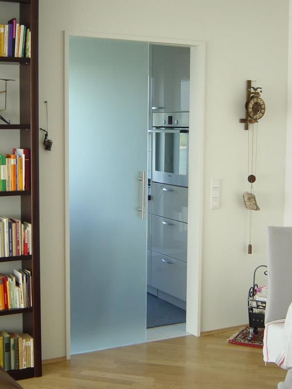 Eine Glasschiebetür in einem Wohnzimmer führt zu einer Küche