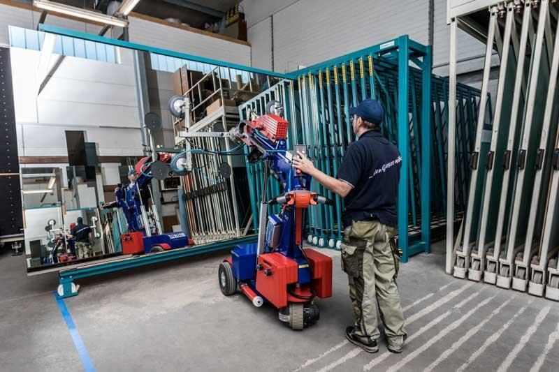 Ein Mann steht neben einer Maschine, die einen großen Spiegel anhebt.