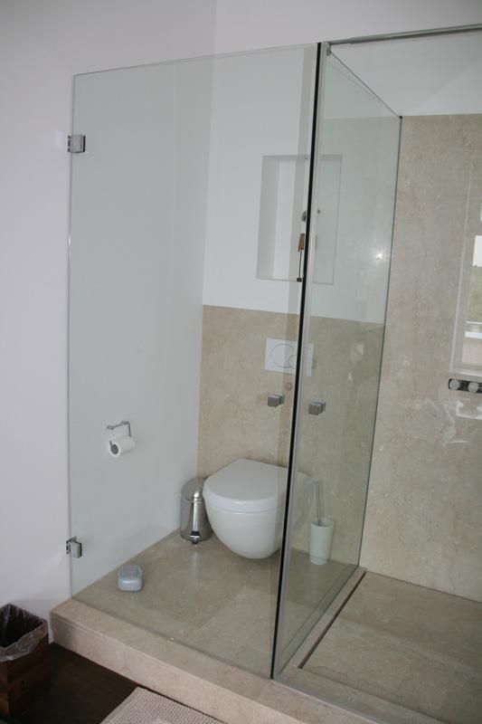 Ein Badezimmer mit Toilette und ebenerdiger Dusche.