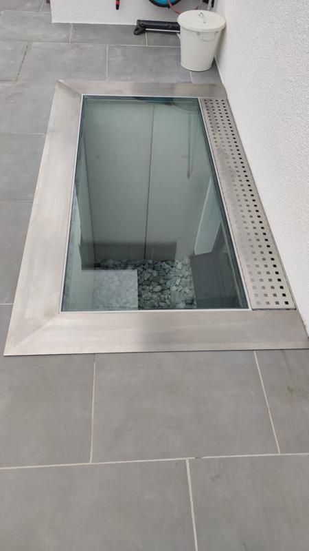 Ein Glasboden in einem Keller mit einem Abfluss.