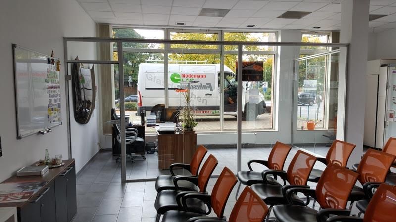 Ein Wartezimmer mit orangefarbenen Stühlen und einem weißen Lieferwagen im Hintergrund.