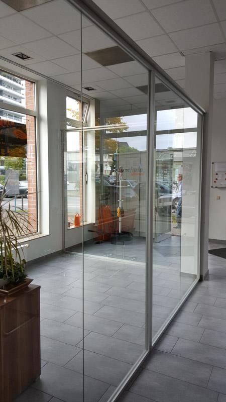 Ein Raum mit vielen Fenstern und einer Glaswand.