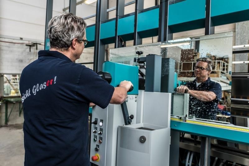 Ein Mann in einem blauen Hemd arbeitet in einer Fabrik an einer Maschine.