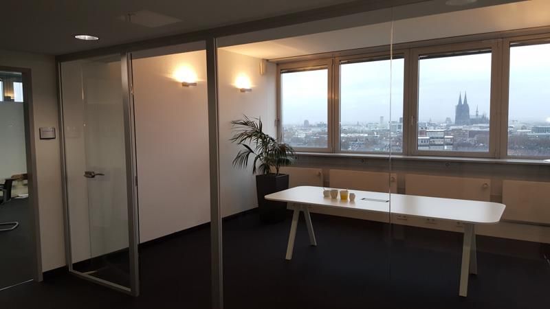 Ein Raum mit einem Tisch und einem Fenster mit Blick auf eine Stadt.